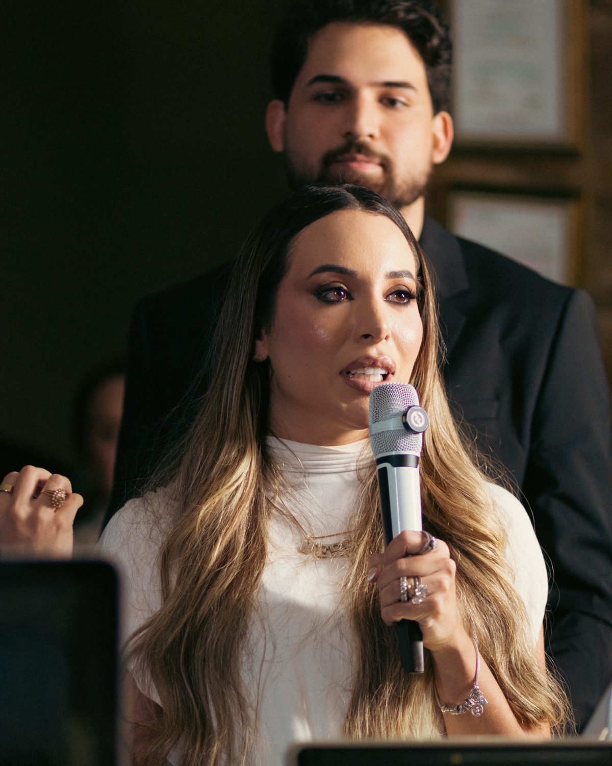 Dra. Ana Clara Porto falando ao microfone, com o Dr. Ítalo Feitosa ao fundo.